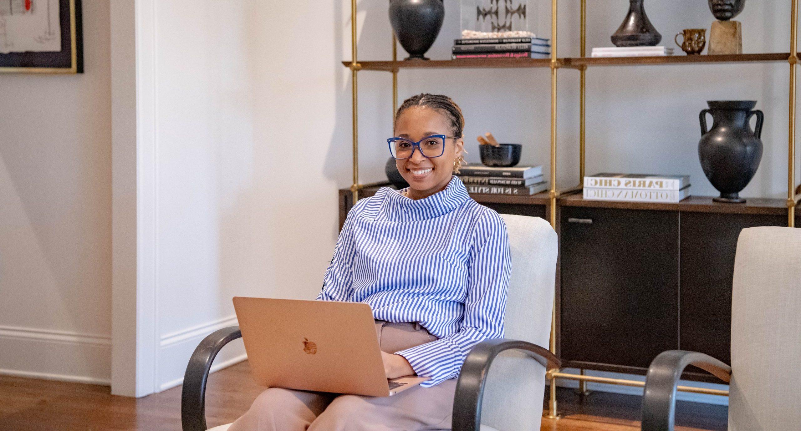 Student sitting in chair in living room with laptop in her lap.